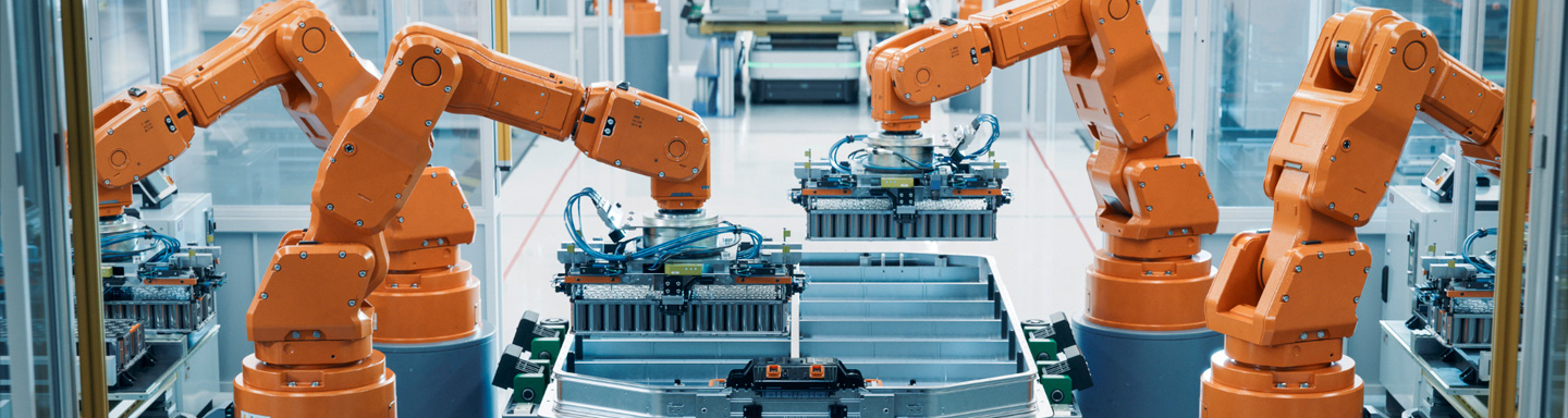 Multiple orange robotic arms operate on an automated production line in a modern factory.